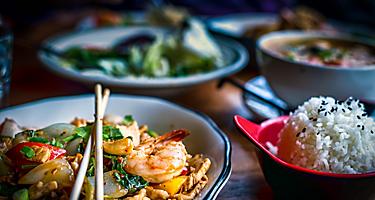 Colorful thai food in bowls with shrimp pad thai and bowls of rice