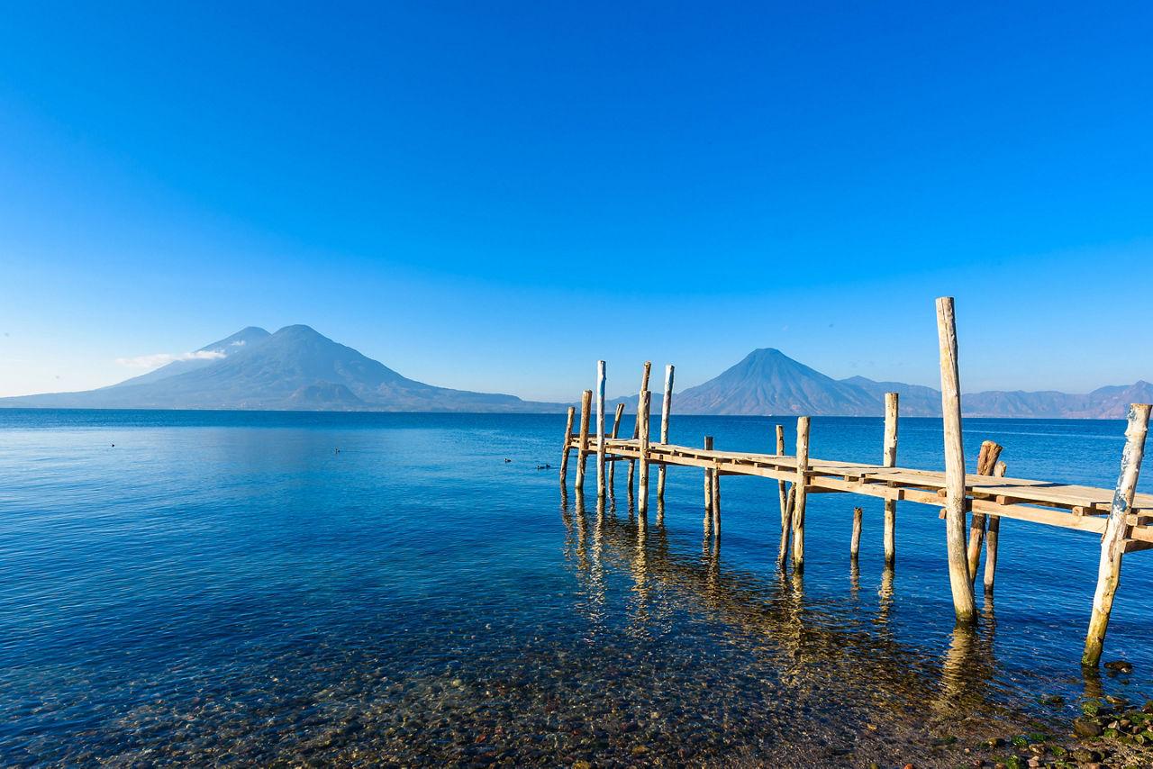 Wooden pier at Lake Atitlan on the beach in Panajachel, Guatemala. With beautiful landscape scenery of volcanoes Toliman, Atitlan and San Pedro in the background.