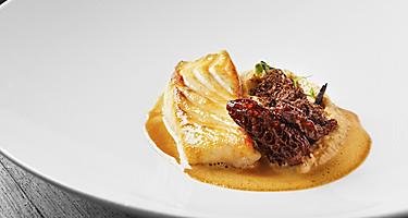 A roasted fillet of halibut and potato puree in a white bowl