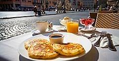 Italian breakfast including pancakes fruits and drinks on the background of Piazza Navona in Rome,Italy
