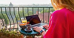 Woman using laptop during breakfast on balcony in Rome Italy
