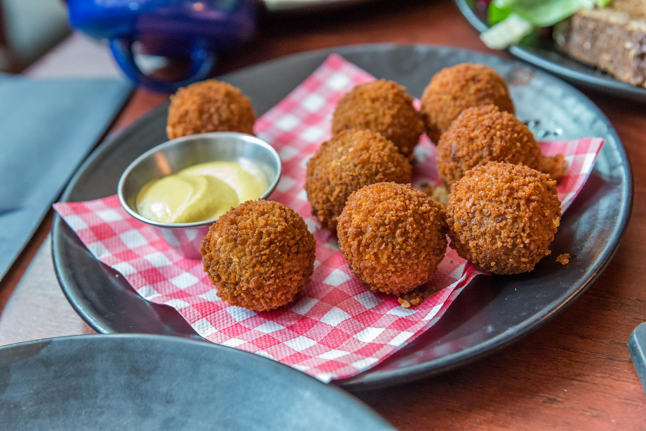 Eight bitterballen on a plate with a dipping sauce