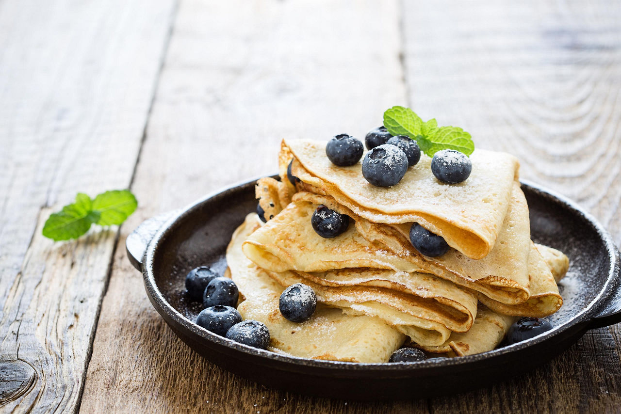 Homemade crepes served with fresh blueberries and powdered sugar on a cast iron skilled, from an eatery in Saguenay, Quebec