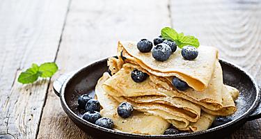 Homemade crepes served with fresh blueberries and powdered sugar on a cast iron skilled, from an eatery in Saguenay, Quebec