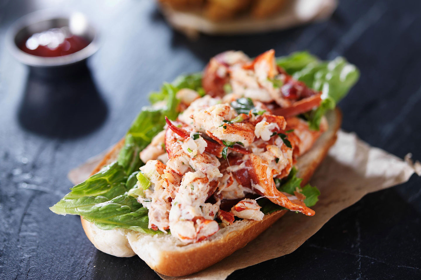 A New Brunswick lobster roll sits on a plate, filled with fresh chilled lobster meat. - Saint John (Bay of Fundy), New Brunswick