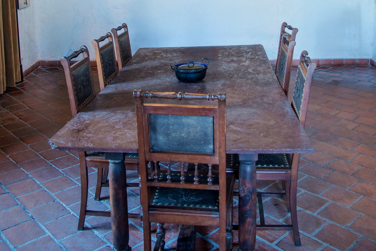Spanish precolonial dining room with old tables and chairs, tile floors.