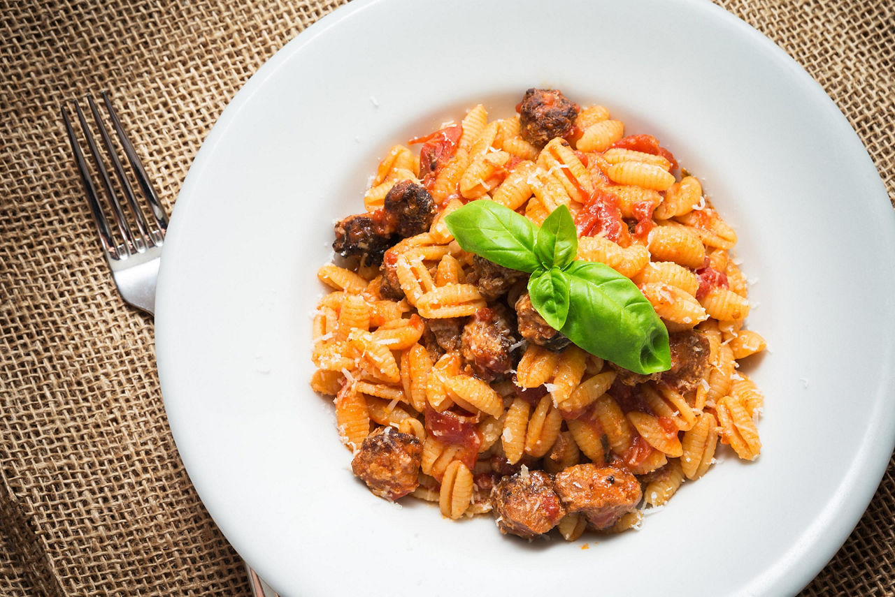 Pasta with tomato sauce and sausage on a white plate