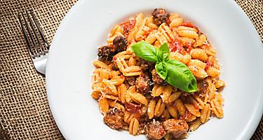 Pasta with tomato sauce and sausage on a white plate
