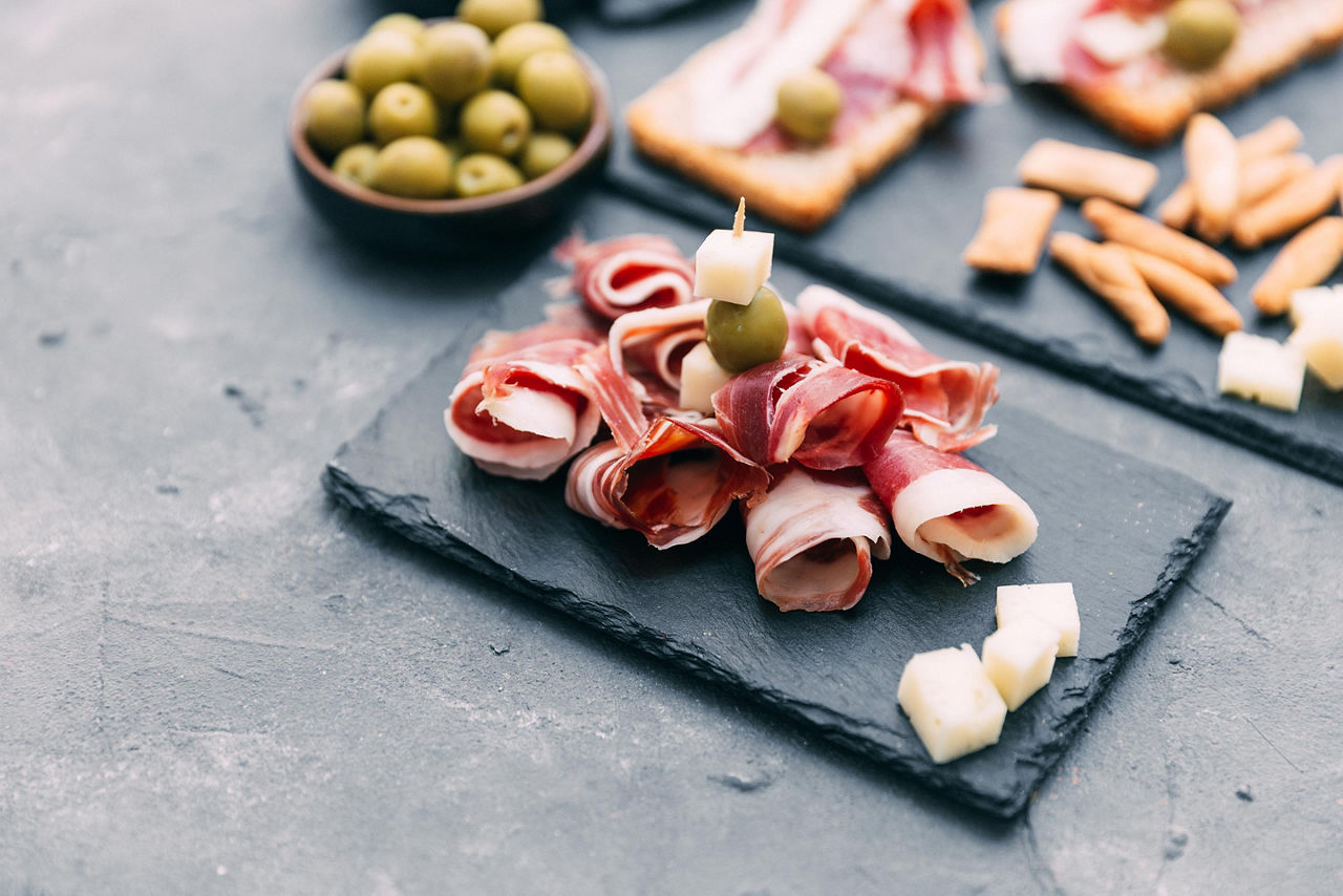 A tapas plate with serrano ham, cheese, and olives