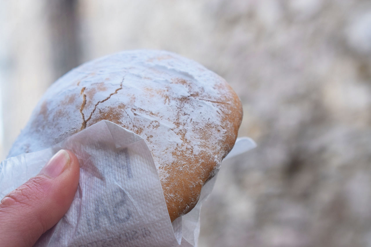Ericino, a type of traditional dessert from Erice (Sicily) with icing sugar filled with lemon cream, held in the hand
