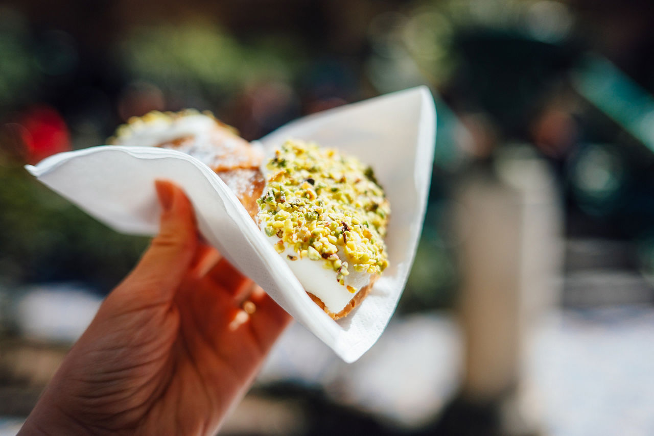 Hand holding fresh Sicilian cannoli at I Segreti del Chiostro, Palermo
