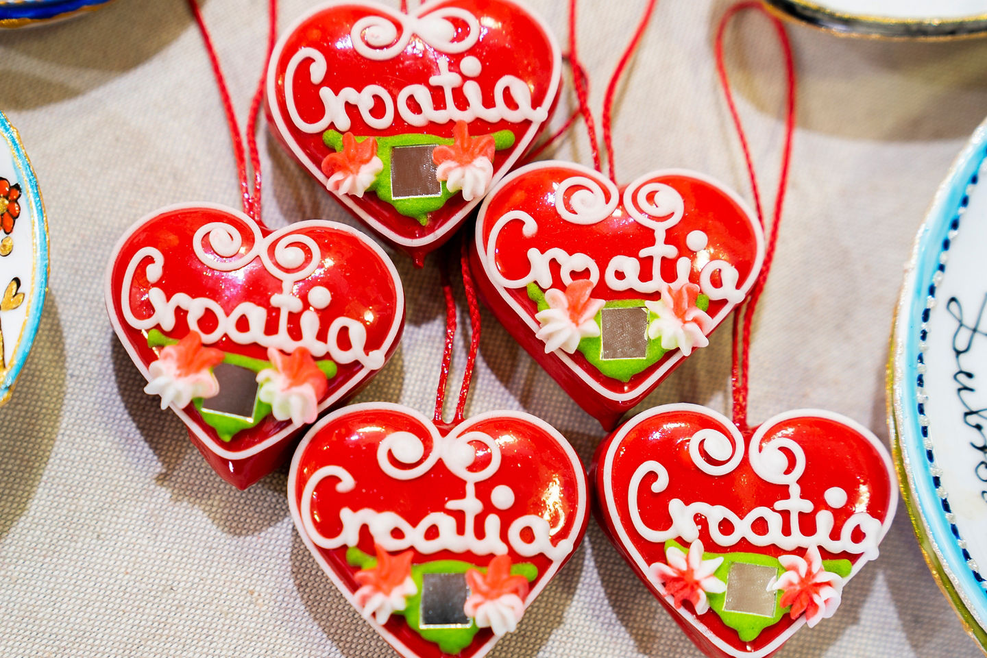 Colorful Croatian licitar heart ornaments hang together, showcasing traditional handcrafted folk art. - Split, Croatia