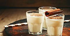Traditional winter eggnog with milk, rum and cinnamon, sprinkle with grated nutmeg, selective focus