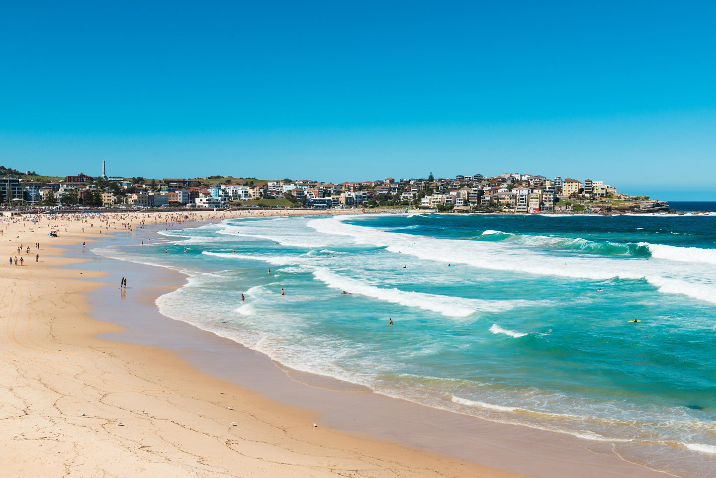 Aerial view of Bondi Beach with turquoise waves and crowded shore.