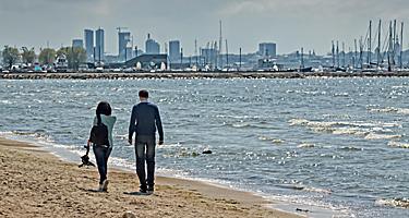 A man and a woman walking on a beach in Tallinn, Estonia