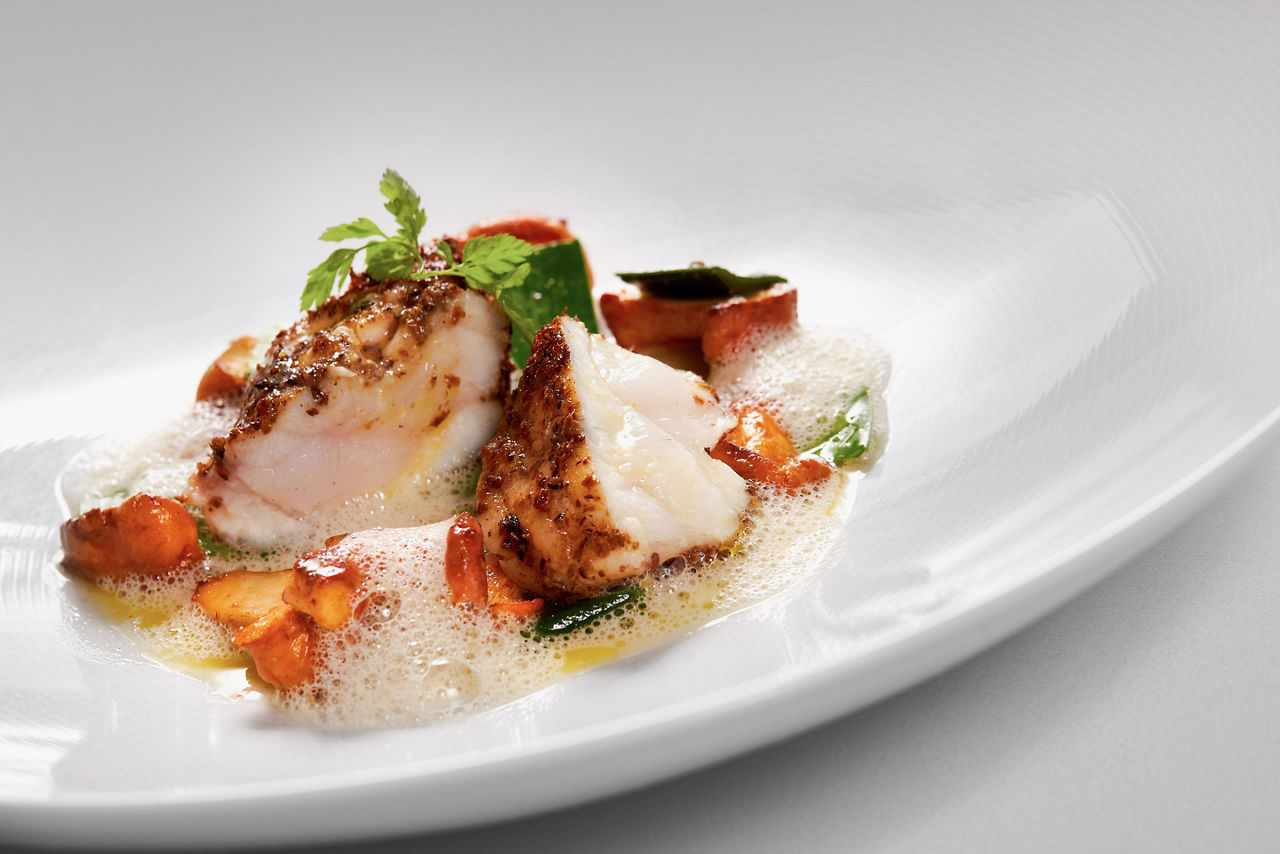 A filet of arctic cod with clarified butter foam on a white plate