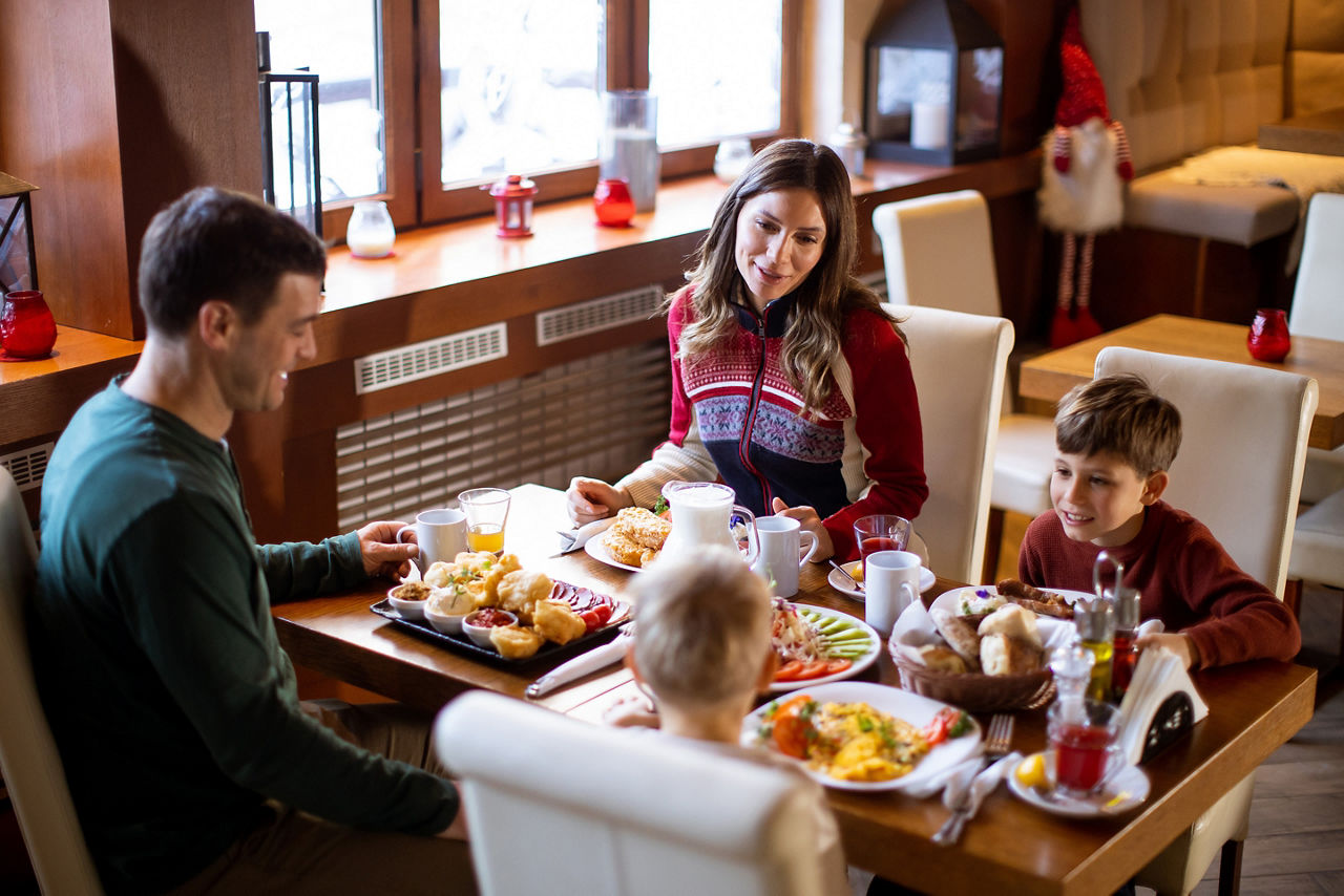 A family of four sits at a wooden table in a restaurant. 