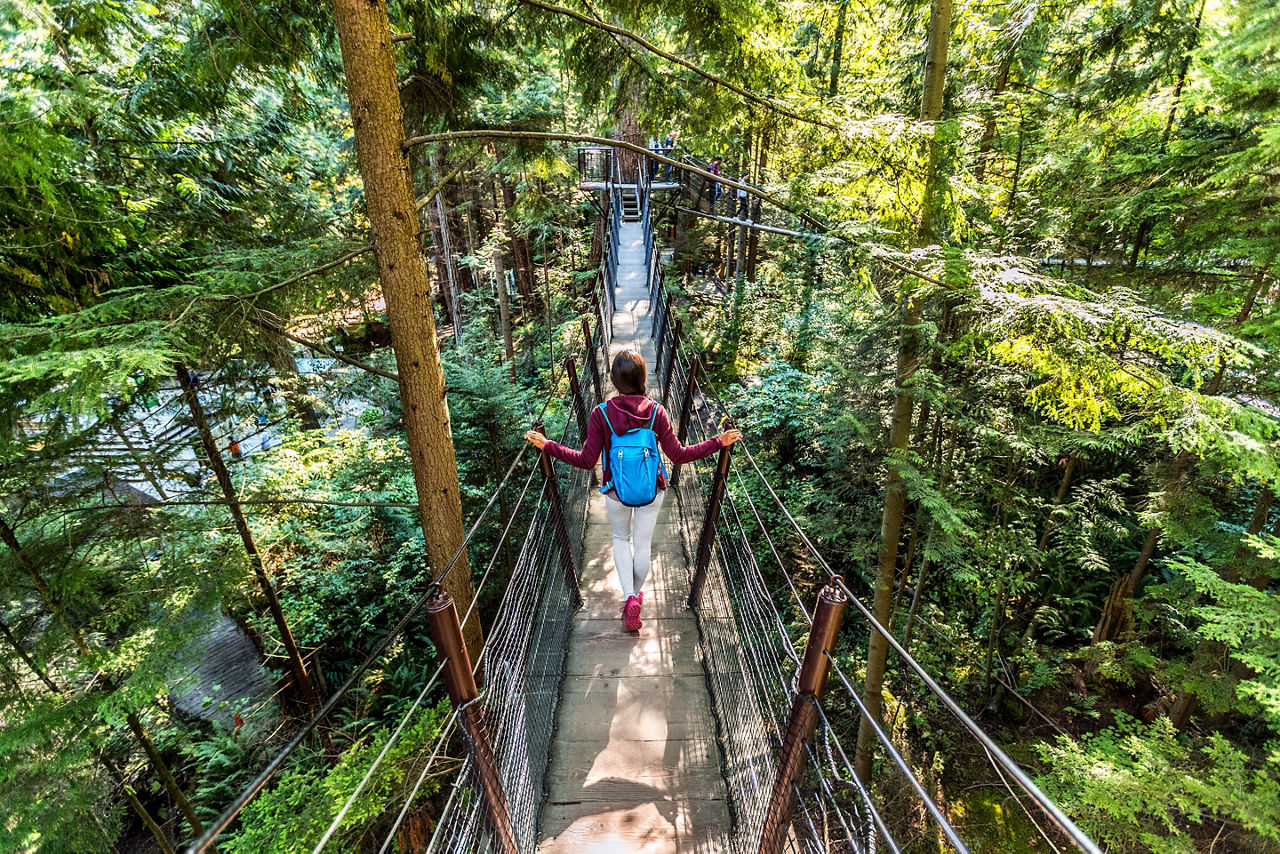 Woman walking in famous attraction Capilano Suspension Bridge in North Vancouver
