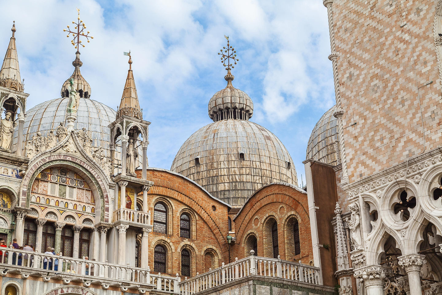 St. Mark’s Basilica displays ornate domes and detailed mosaics above Venice’s busy square. - Venice, Italy