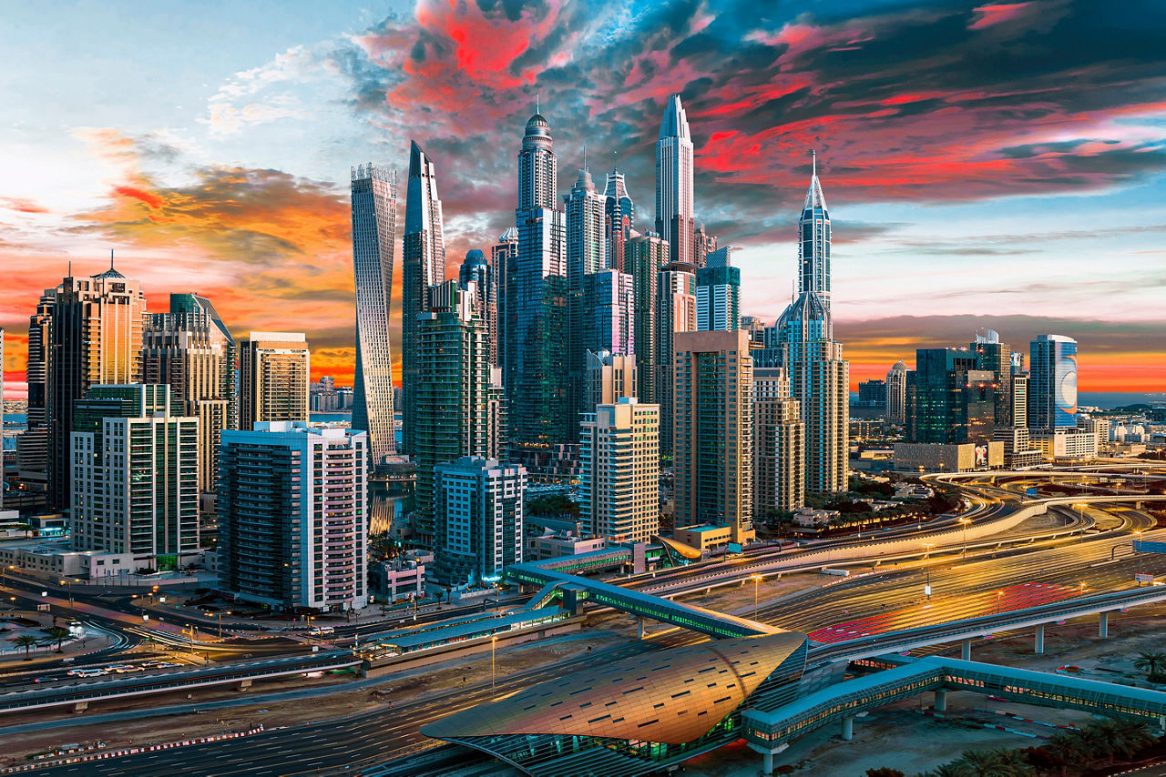 Aerial view of the Dubai skyline in front of a colorful sunset. Dubai