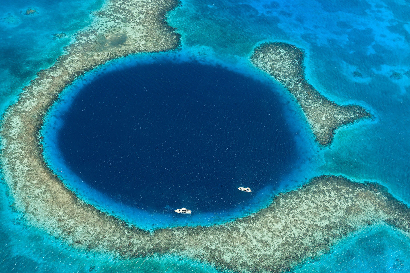 A vast circular sinkhole of deep blue water contrasts sharply with Belize’s lighter turquoise sea. - Belize City, Belize