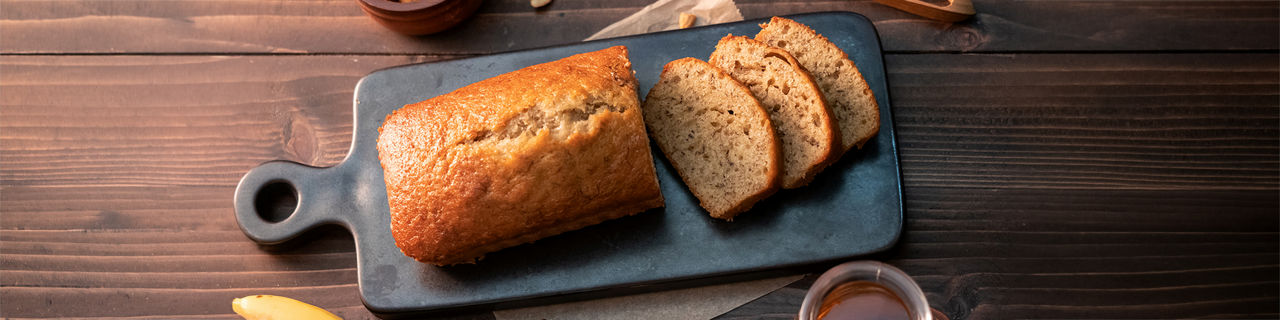 Homemade banana bread pound sliced with cashew nuts and honey on wooden table.