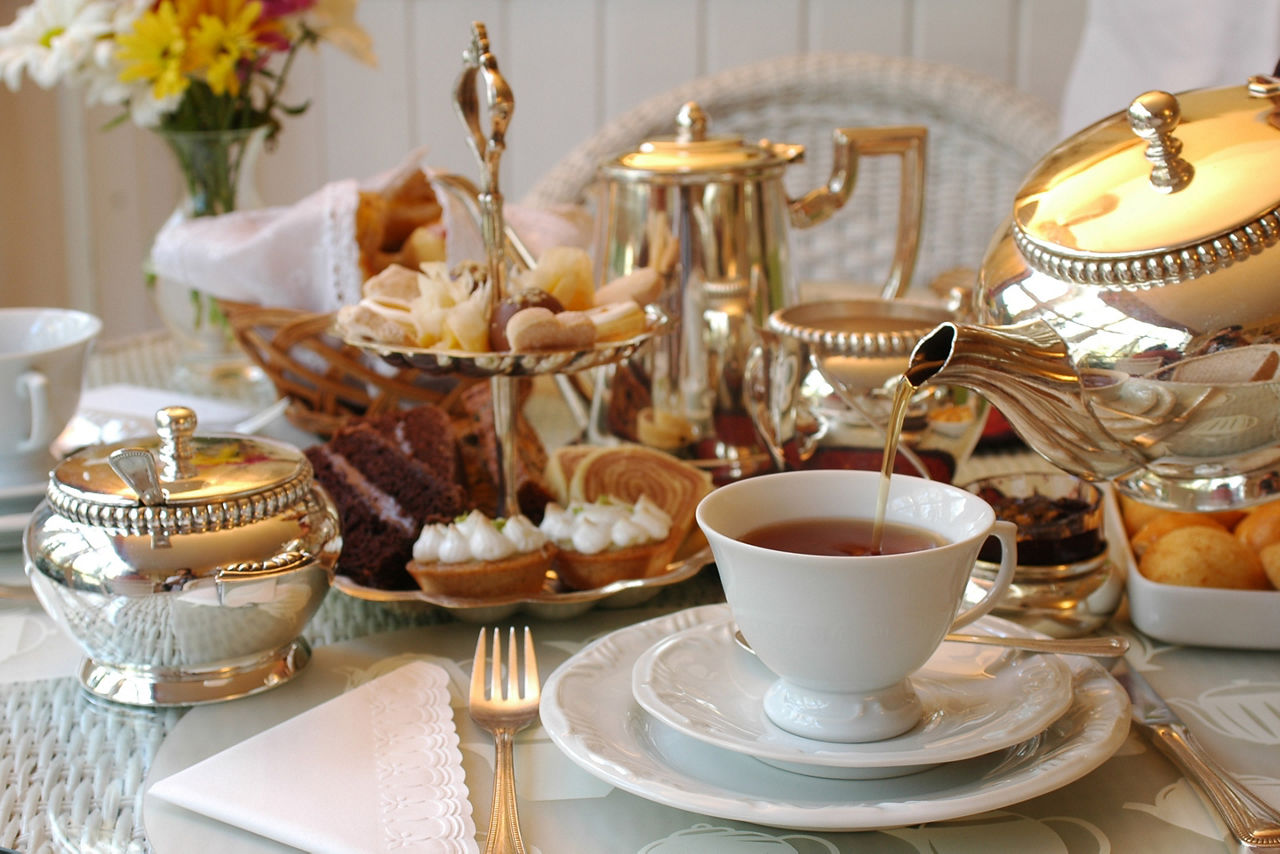 Tea being poured during an English afternoon in the UK. London. Caption:   Afternoon tea is a simply scrumptious affair.