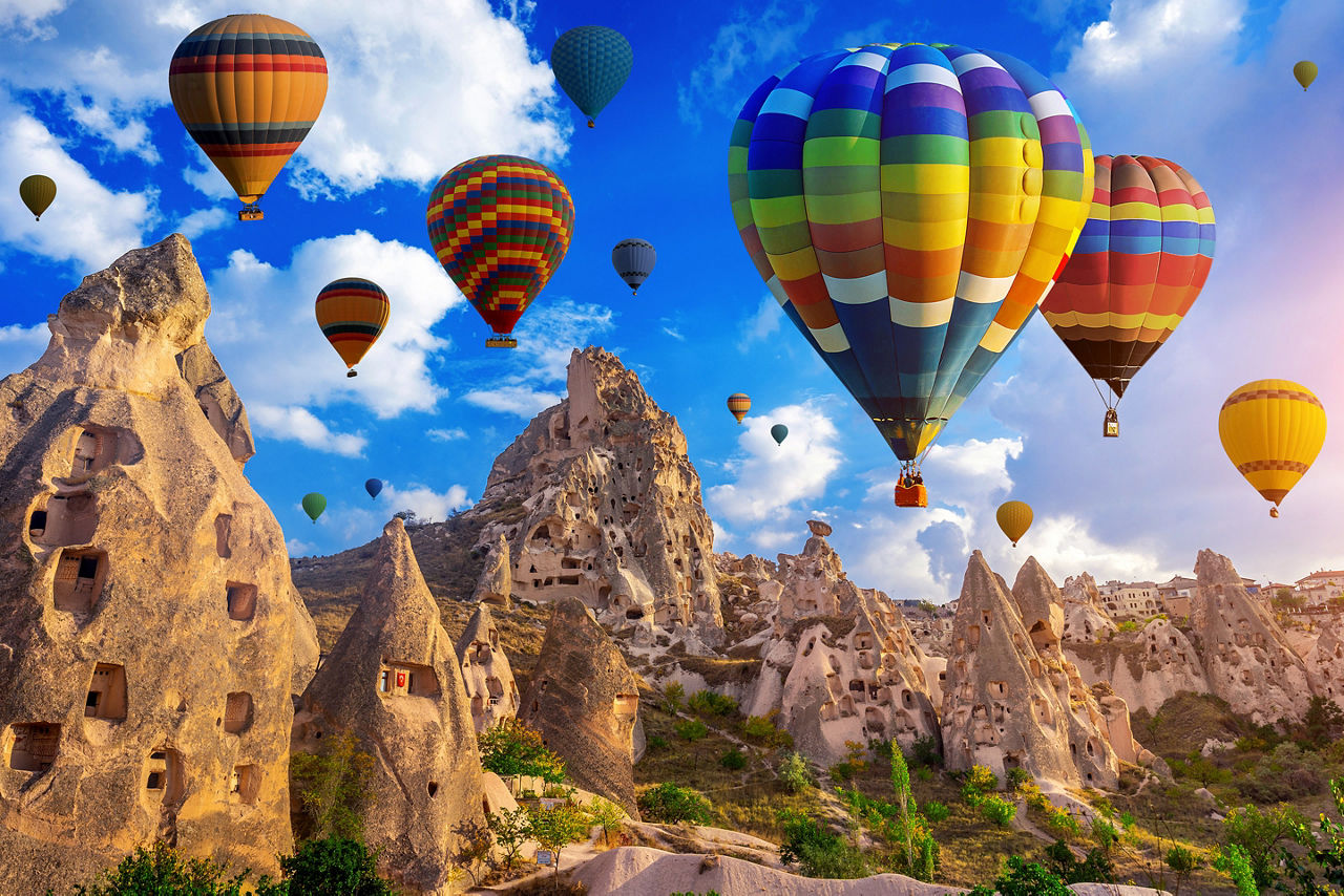 Colorful hot air balloon riders hovering over the rock formations of Cappadocia, Turkey.
