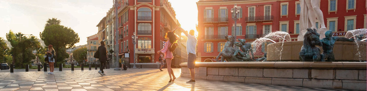 France, Côte d''Azur, French Riviera, couple, people walking near fountain in large plaza