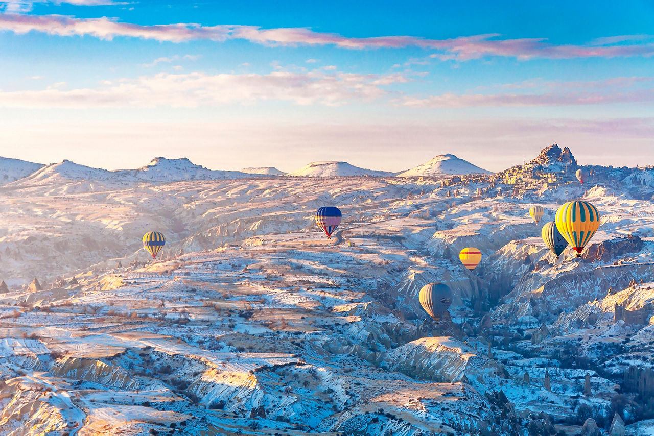 Hot air balloon riders flying over snow covered mountains. Turkey.