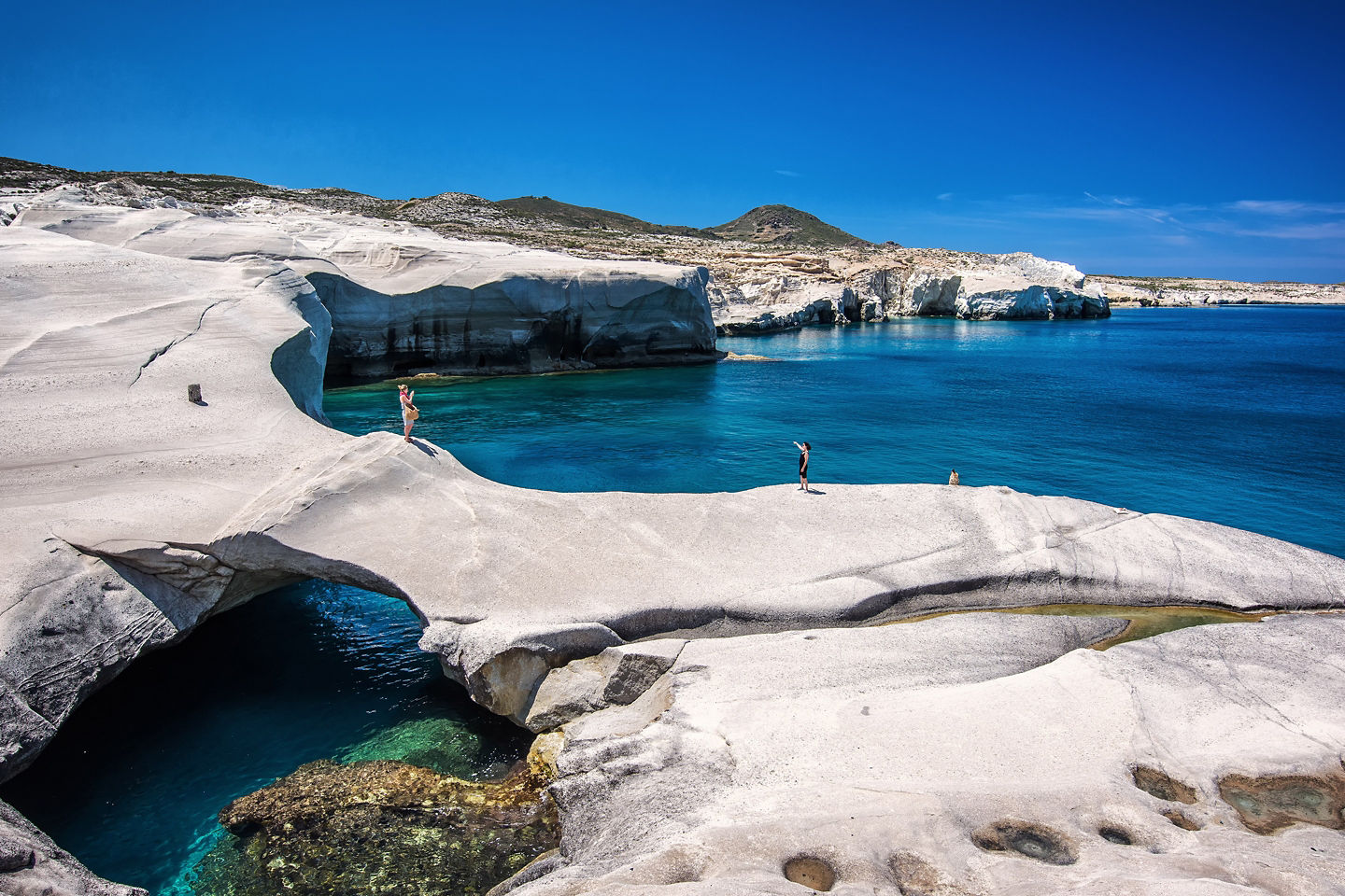 Sarakiniko Beach's white volcanic cliffs curve above turquoise water along Milos’s bright coastline. - Corfu, Greece