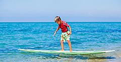 Little boy with surf board learning surfing Hawaii