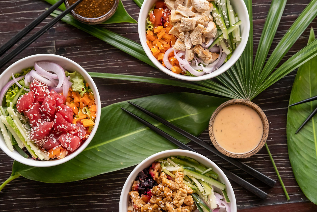 Variety of healthy organic Hawaiian foods served on wooden table with tropical leaves. Hawaii.