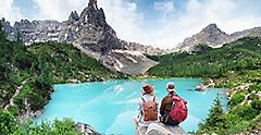 Travelers couple look at the mountain lake. Travel and active life concept with team. Adventure and travel in the mountains region in Dolomite alps, Italy