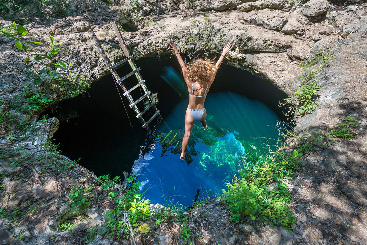 Mexico Costa Maya Woman Jumping into Cenote Azul