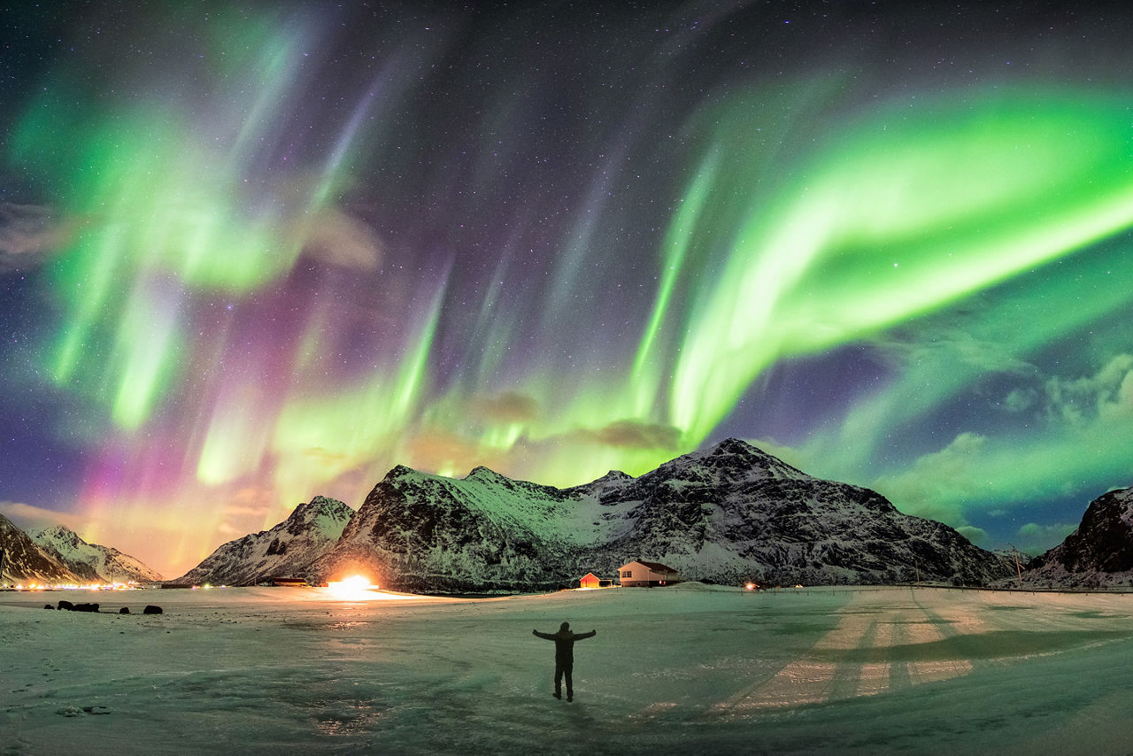 Aurora borealis (Northern lights) over mountain with one person at Skagsanden beach