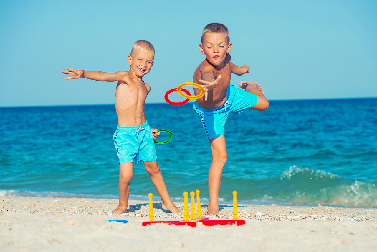 Brothers playing a game throwing rings on the beach.