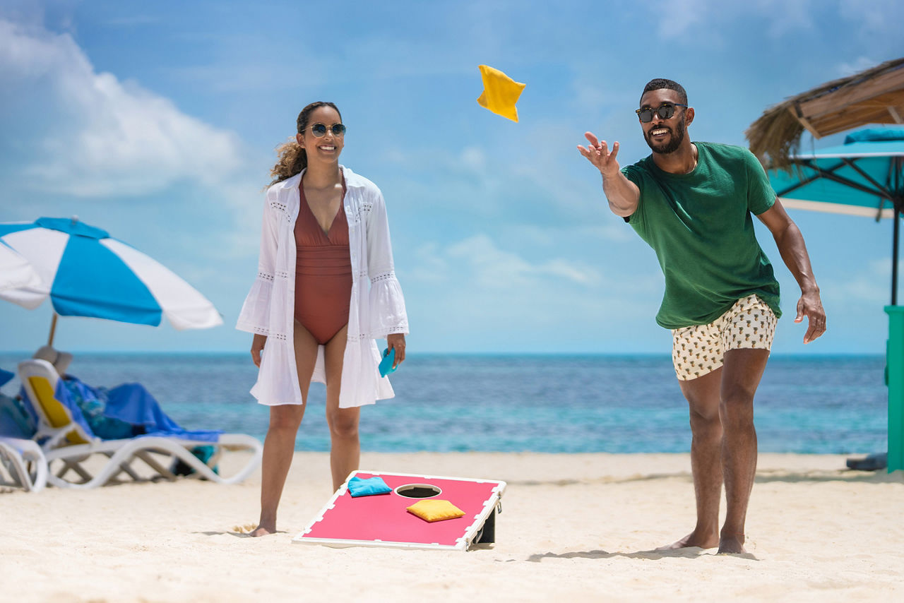 RBC Paradise Island, African American playing cornhole, yellow bag, private island, fun