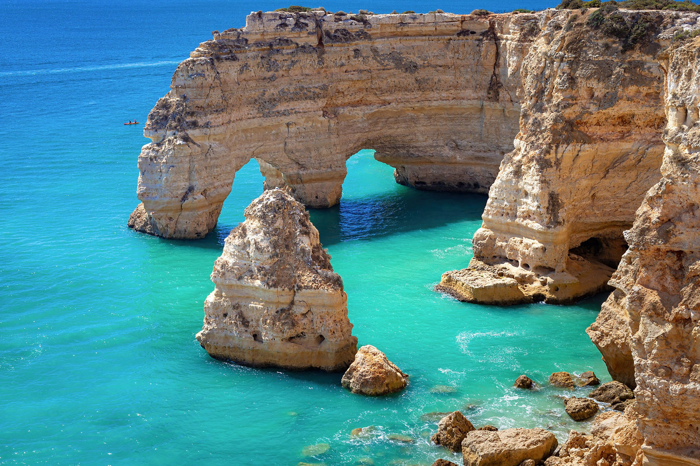 Golden sea arch rises above clear turquoise water along Algarve coastline. - Carvoeiro, Portgual
