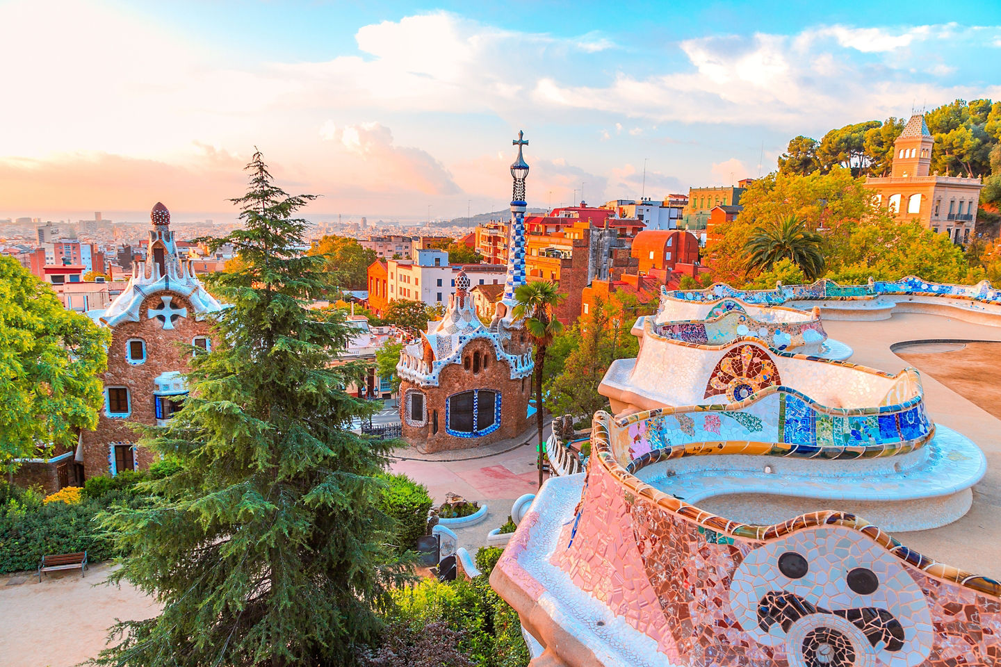 Park Güell’s colorful mosaic terraces overlook Barcelona during golden hour. - Barcelona, Spain