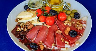 Antipasto plate of Njeguski prsut cured meat, cheese, olive oil, fresh tomatoes and nuts.