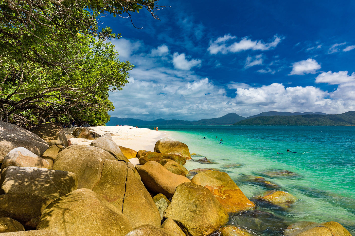 Nudey Beach with turquoise water, white sand, rocks, and greenery.