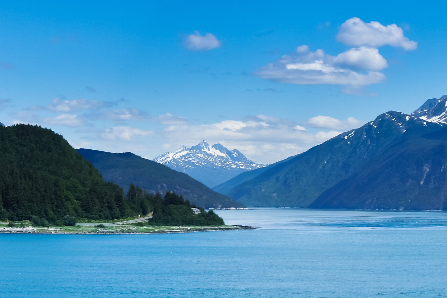 Haines sits along calm blue water, backed by towering snow‑covered mountains and forested slopes. - Haines, Alaska