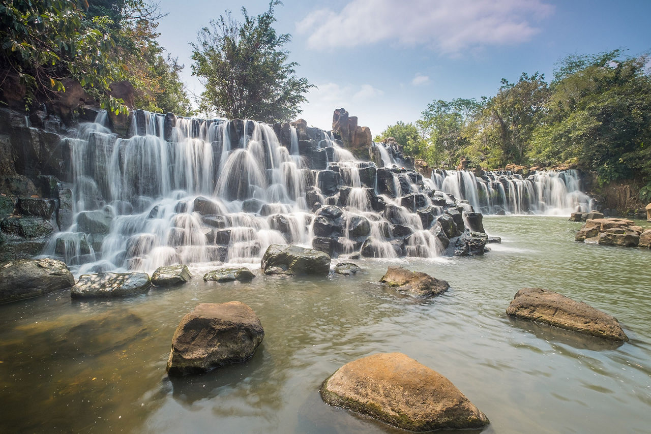 Wide view of Giang Dien Waterfall in Dong Nai Province, Vietnam, featuring cascading water over rock formations surrounded by lush tropical gree