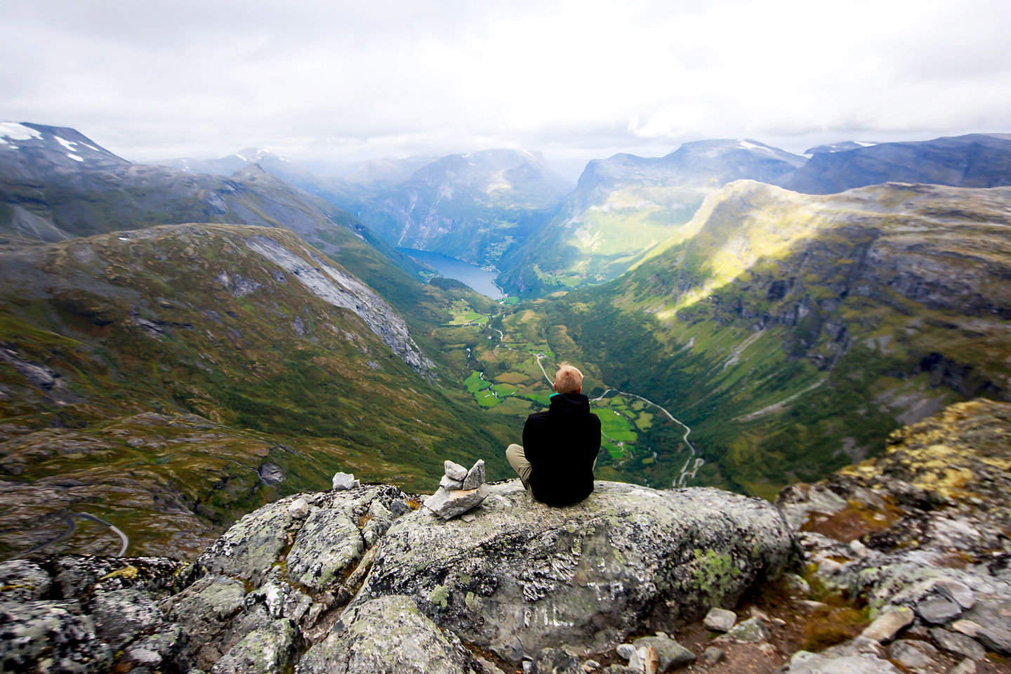 Steep green cliffs surround a calm fjord. - Ålesund, Norway