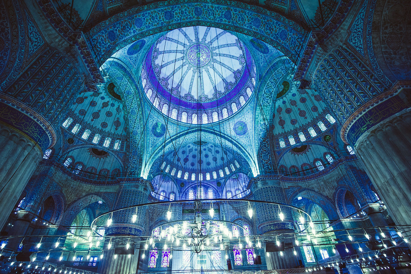 Blue Mosque interior glows with warm light across patterned carpets, arches, and towering columns. - Istanbul, Turkey