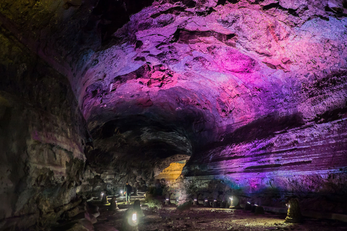 Illuminated walkways reveal Manjanggul Cave’s lava‑formed corridor, lined with rugged volcanic rock textures. - Jeju, South Korea