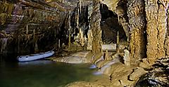 Rubber raft parked by stalagmites and stalactites in the Kalvaria hall in Križna Jama karst cave in the early summer