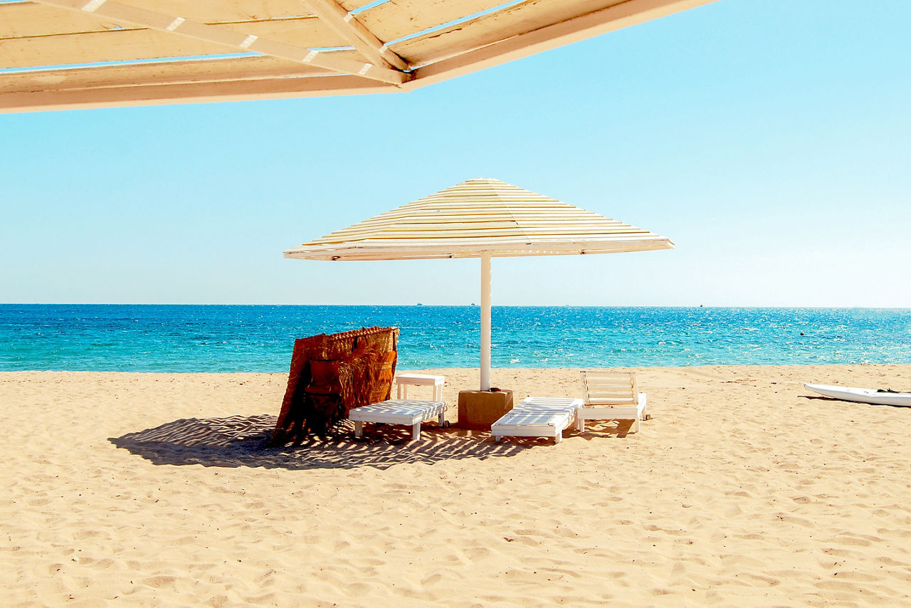 Egypt, Safaga, the Red Sea coast, a straw umbrella and sun beds on the golden sand.