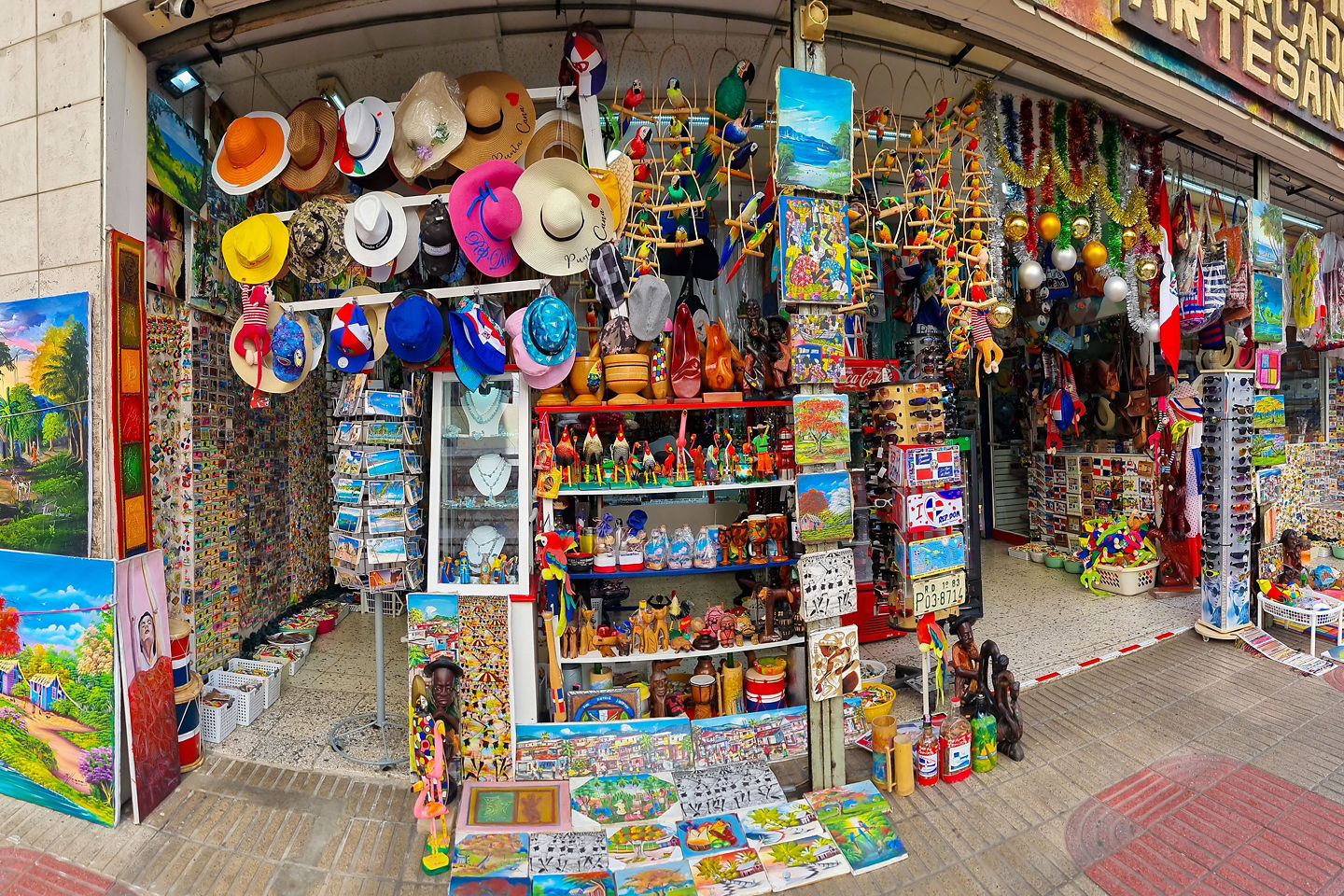 Colorful Dominican souvenirs fill a small shop, with hats, crafts, and vibrant displays lining the walls. - Samaná, Dominican Republic